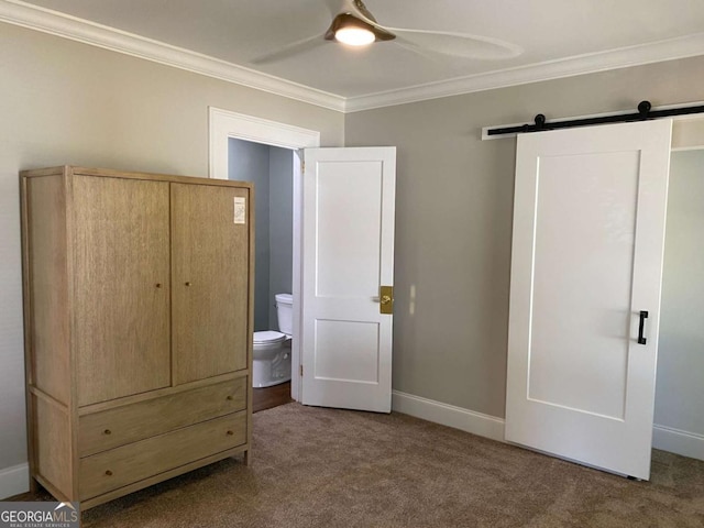 unfurnished bedroom featuring carpet, a barn door, ornamental molding, ceiling fan, and baseboards