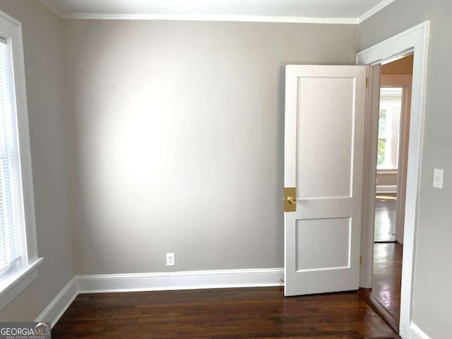 spare room with baseboards, dark wood finished floors, and crown molding