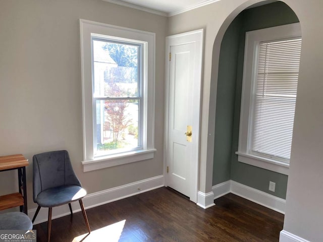 living area with baseboards, arched walkways, dark wood-style flooring, and ornamental molding