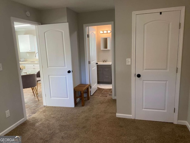 unfurnished bedroom with carpet flooring, a sink, baseboards, and ensuite bathroom