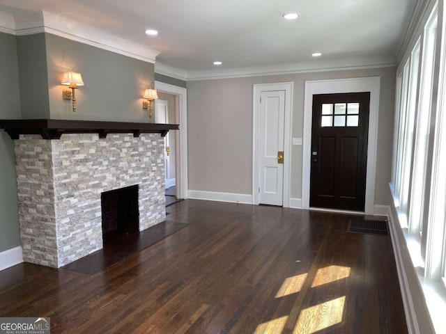 foyer entrance featuring crown molding, a fireplace, dark wood finished floors, and baseboards