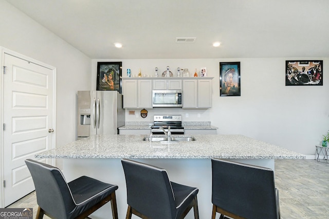 kitchen featuring a kitchen bar, visible vents, stainless steel appliances, and a sink