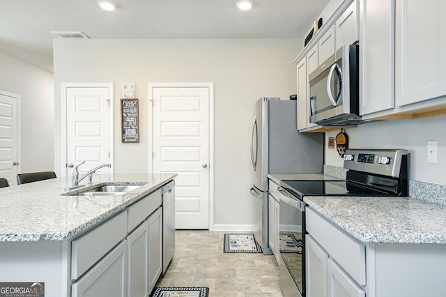 kitchen with baseboards, stainless steel appliances, a sink, and recessed lighting