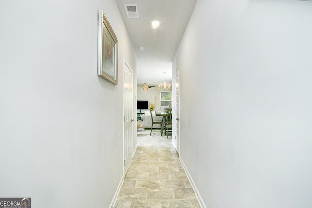 hallway featuring stone finish flooring, visible vents, and baseboards