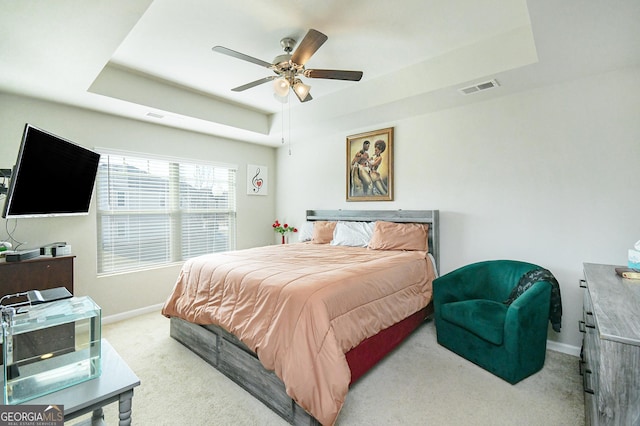 carpeted bedroom with a ceiling fan, a raised ceiling, visible vents, and baseboards