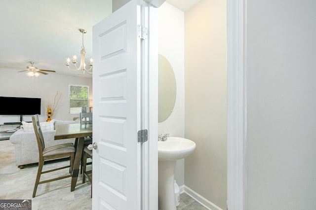 bathroom featuring a sink, baseboards, and ceiling fan with notable chandelier