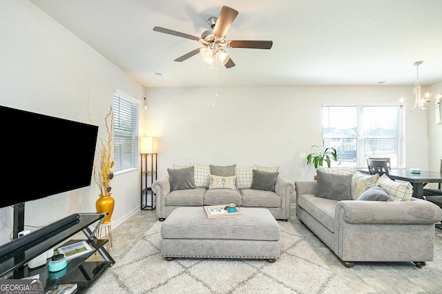 living room with ceiling fan with notable chandelier, visible vents, and baseboards