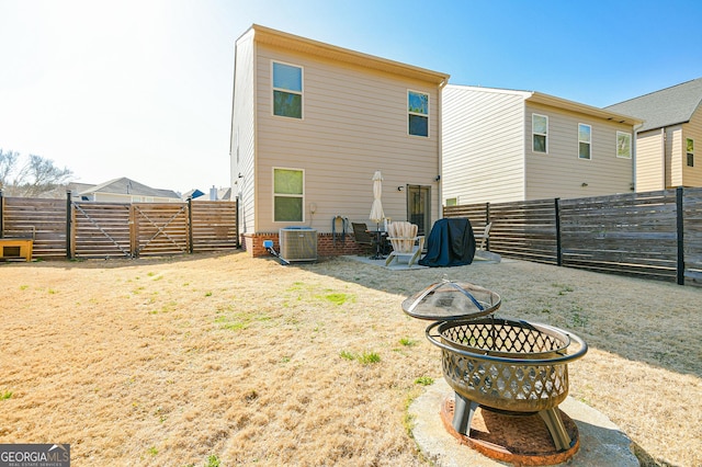 back of property featuring a lawn, a fenced backyard, a gate, and central air condition unit