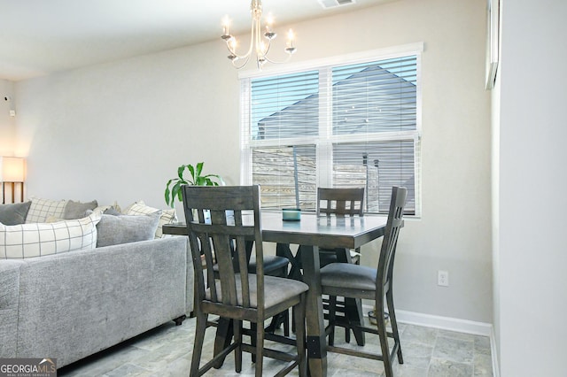 dining area featuring baseboards, stone finish flooring, visible vents, and an inviting chandelier