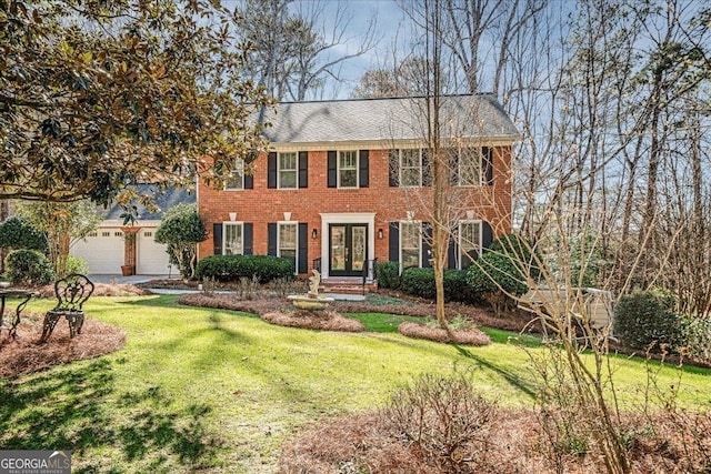 colonial home featuring french doors, an attached garage, brick siding, and a front yard