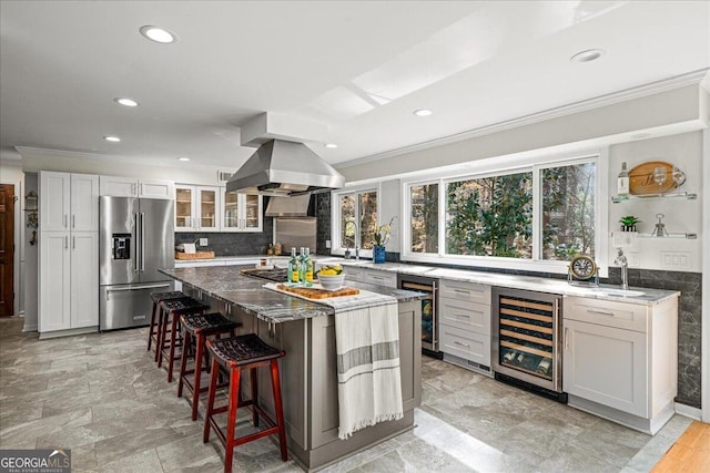 kitchen featuring beverage cooler, plenty of natural light, high end refrigerator, and island range hood