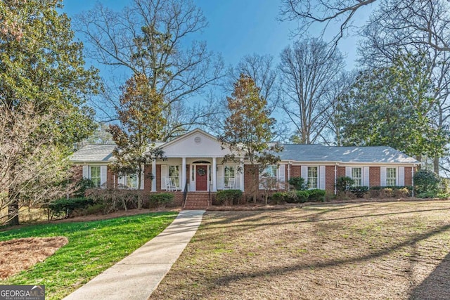 view of front of home with covered porch, brick siding, and a front lawn