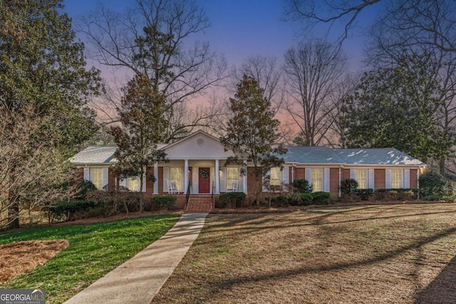 view of front facade featuring a front yard, covered porch, and brick siding