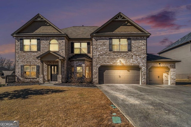 view of front of house with a yard, concrete driveway, and brick siding