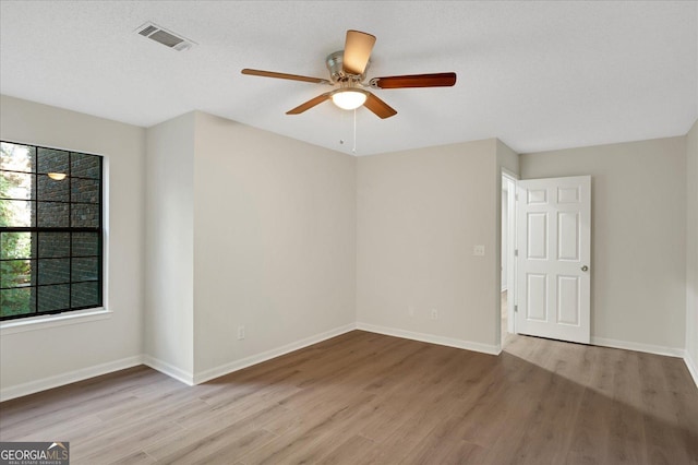 empty room featuring visible vents, ceiling fan, a textured ceiling, wood finished floors, and baseboards