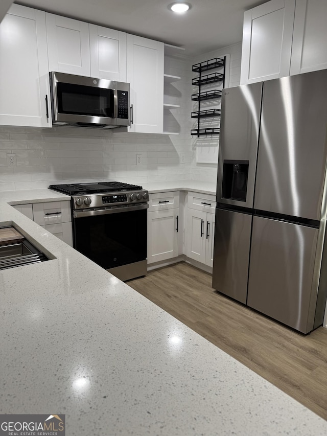 kitchen featuring tasteful backsplash, appliances with stainless steel finishes, white cabinets, and light stone counters