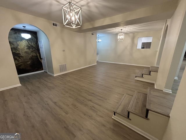 unfurnished living room with visible vents, arched walkways, wood finished floors, and a chandelier