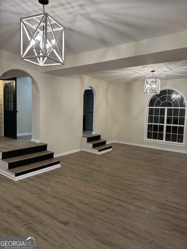 interior space with an inviting chandelier, baseboards, arched walkways, and wood finished floors