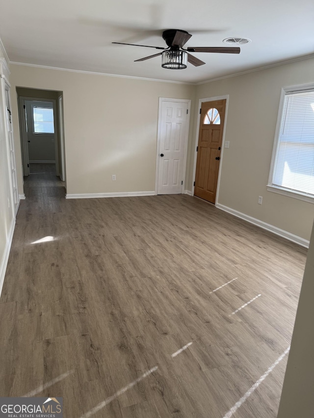 entryway featuring baseboards, visible vents, crown molding, and wood finished floors