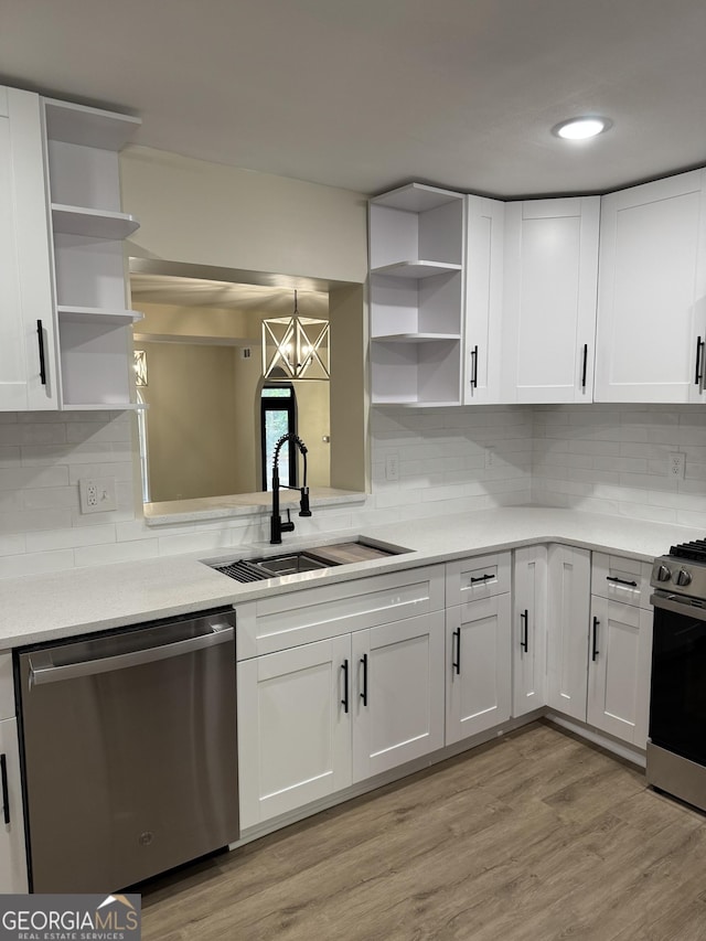 kitchen featuring open shelves, light countertops, appliances with stainless steel finishes, a sink, and light wood-type flooring