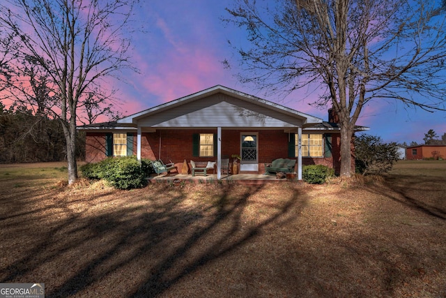 view of front of property with brick siding, a porch, and a front yard