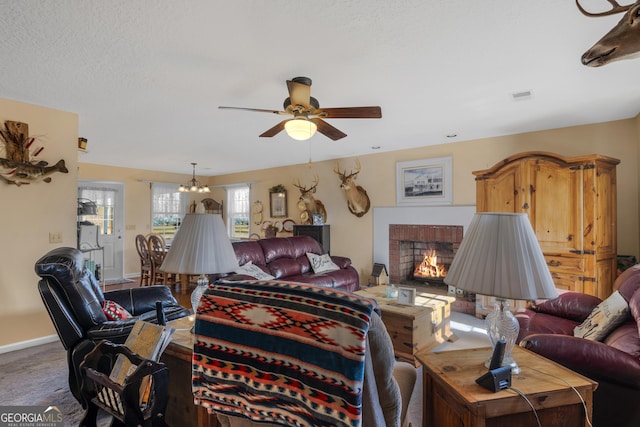 living area with carpet, a fireplace, a textured ceiling, baseboards, and ceiling fan with notable chandelier