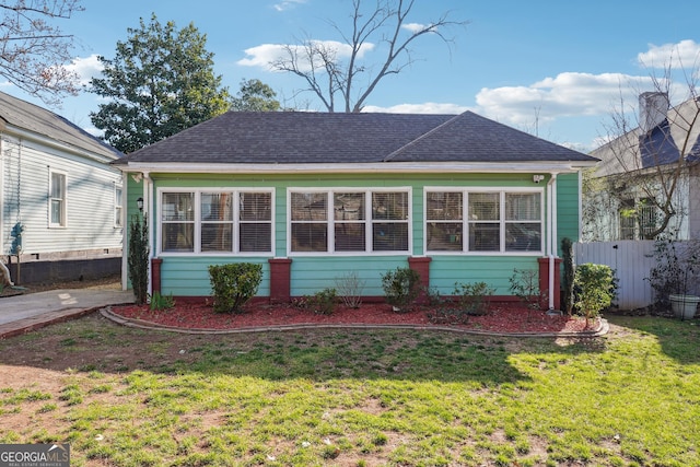 back of house with a yard, roof with shingles, and fence