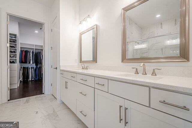 full bathroom with a marble finish shower, a walk in closet, double vanity, marble finish floor, and a sink