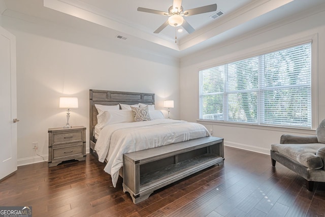 bedroom with a tray ceiling, visible vents, and dark wood finished floors