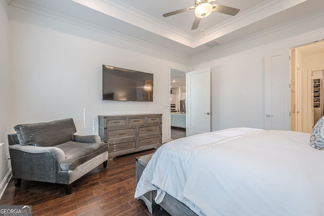 bedroom with a ceiling fan, visible vents, a tray ceiling, dark wood-type flooring, and crown molding