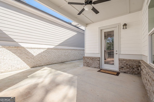 view of exterior entry with brick siding, a patio, and a ceiling fan