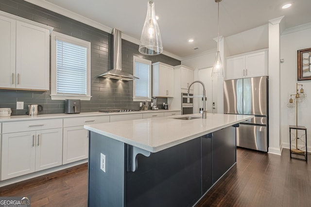 kitchen featuring wall chimney range hood, ornamental molding, freestanding refrigerator, and a sink