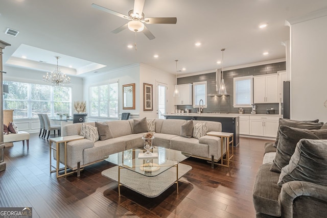 living room featuring dark wood finished floors, a raised ceiling, a healthy amount of sunlight, and visible vents