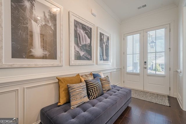 interior space featuring a wainscoted wall, visible vents, dark wood-style flooring, crown molding, and a decorative wall