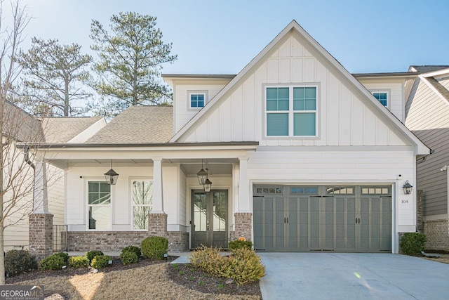 view of front of home featuring board and batten siding, driveway, french doors, and roof with shingles