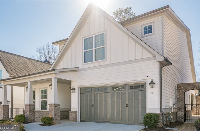 view of front facade featuring stone siding, a garage, board and batten siding, and driveway