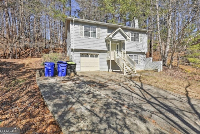 split foyer home featuring a garage, concrete driveway, and a chimney