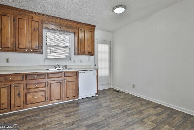 kitchen featuring brown cabinetry, dishwasher, dark wood-type flooring, light countertops, and a sink