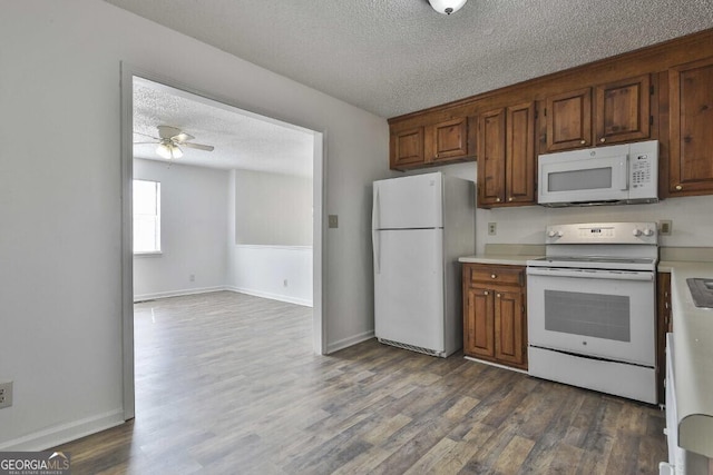 kitchen featuring a textured ceiling, white appliances, a ceiling fan, light countertops, and dark wood finished floors