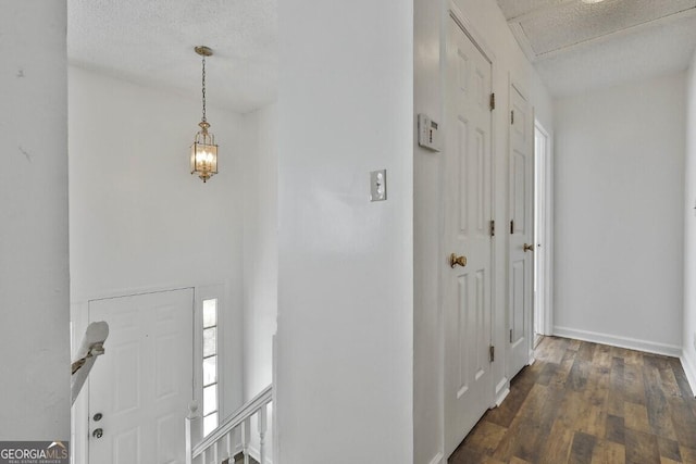 foyer with a textured ceiling, baseboards, and wood finished floors