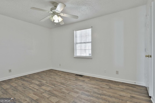 spare room featuring a textured ceiling, wood finished floors, visible vents, and baseboards