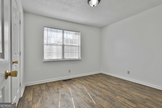 unfurnished room featuring visible vents, a textured ceiling, baseboards, and wood finished floors