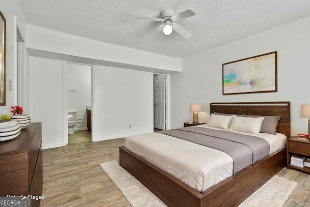 bedroom with a textured ceiling, wood finished floors, and ensuite bathroom