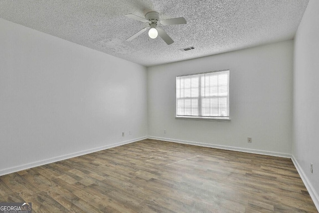 spare room featuring ceiling fan, wood finished floors, and visible vents