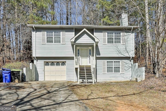 bi-level home featuring driveway, a chimney, and an attached garage