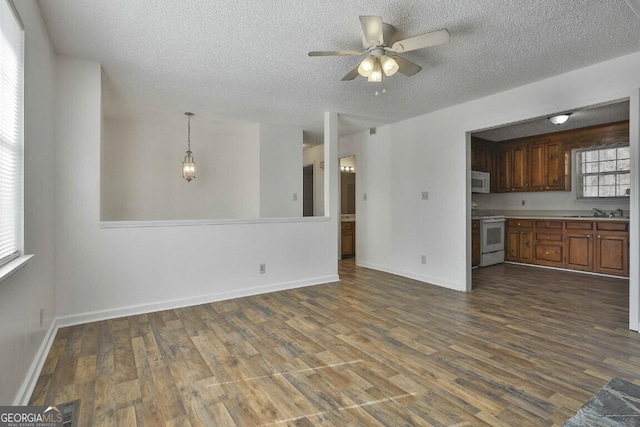 unfurnished living room with dark wood-style floors, a textured ceiling, a sink, and a ceiling fan