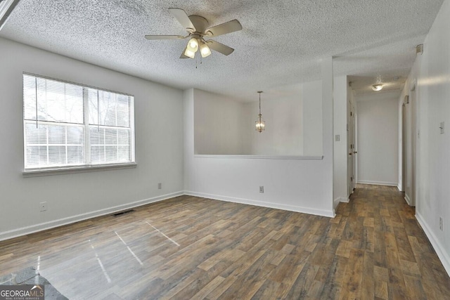 spare room with baseboards, visible vents, ceiling fan, wood finished floors, and a textured ceiling