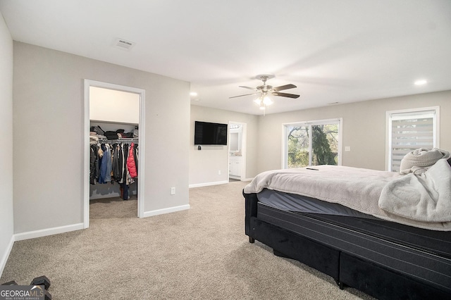 bedroom with connected bathroom, carpet floors, visible vents, baseboards, and a walk in closet