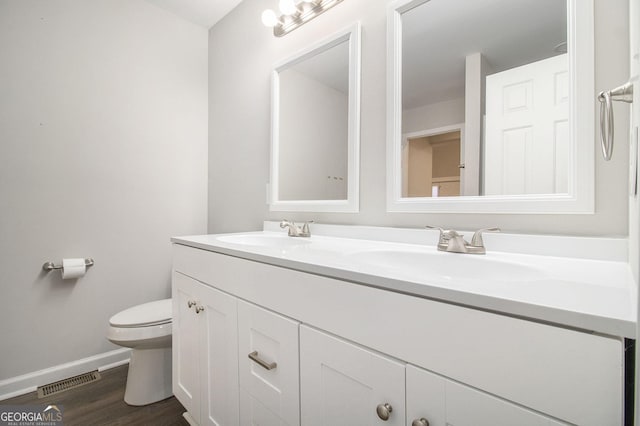 bathroom featuring double vanity, baseboards, visible vents, toilet, and a sink