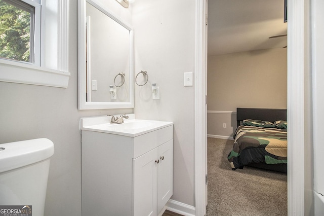 bathroom with toilet, vanity, and baseboards